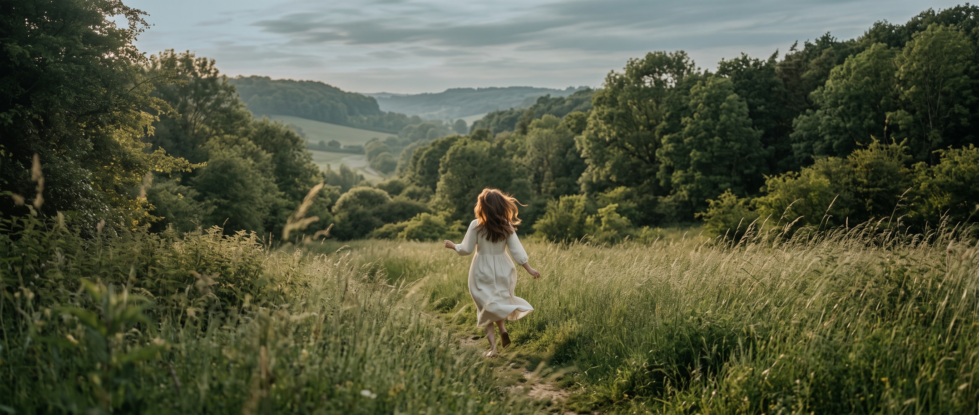 A woman walking a path through a summer meadow